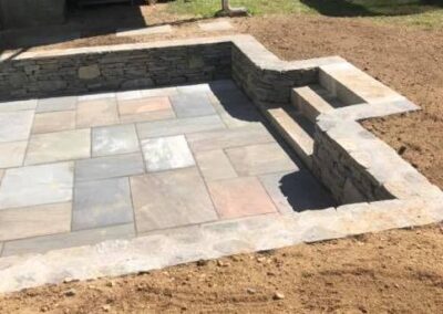 photo of a sunken bluestone patio with stairs by Stone Builders Masonry